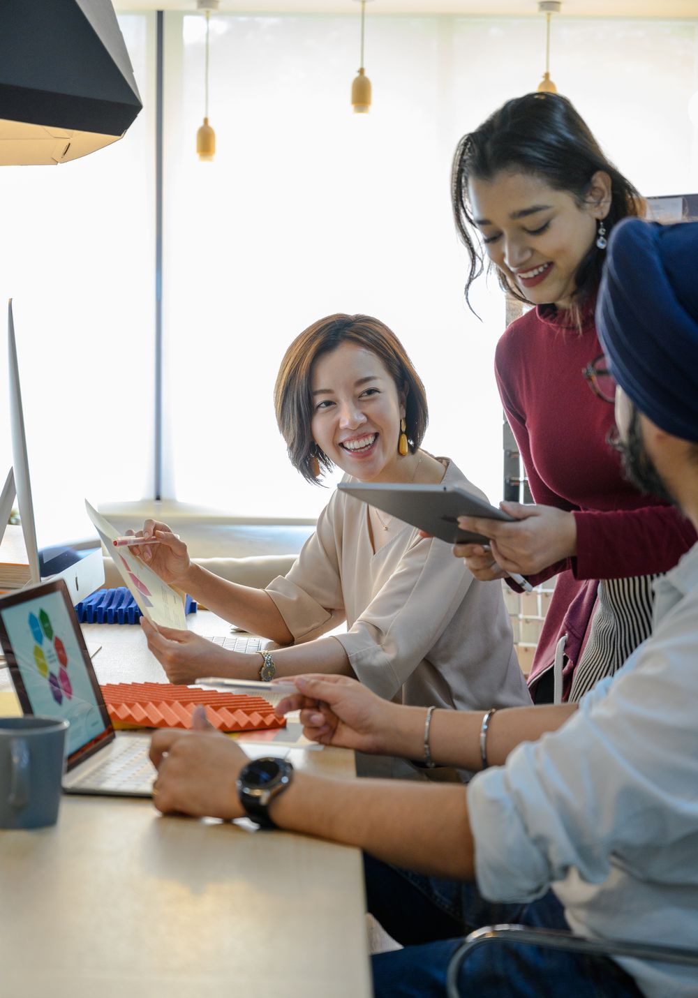 Equipe sorrindo enquanto trabalha com notebook e tablet